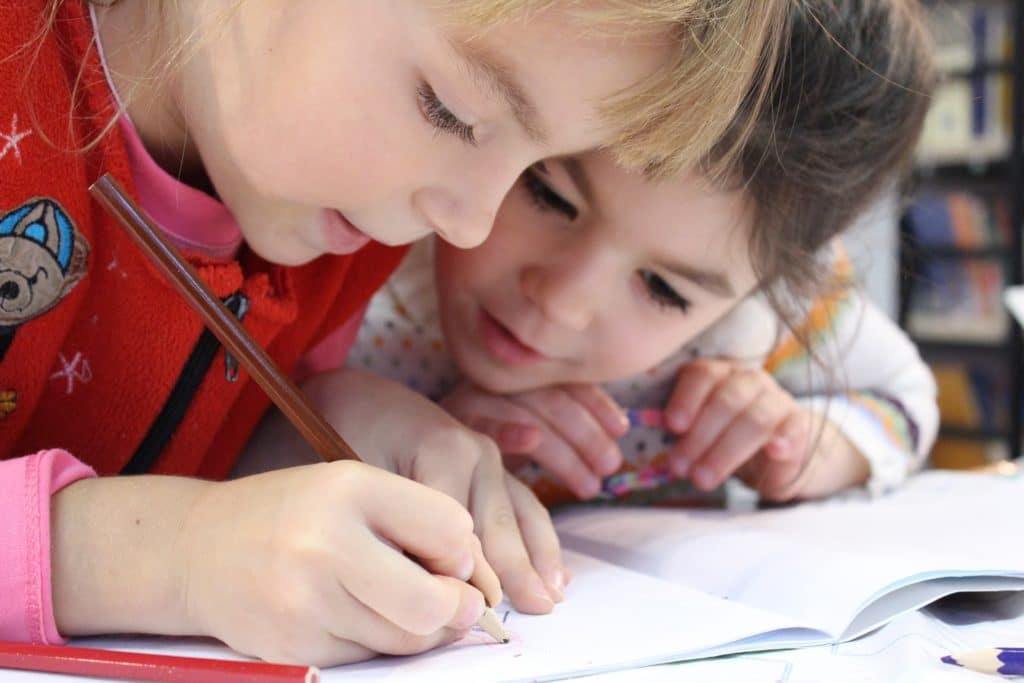 Two girls use colored pencils at a child care center.