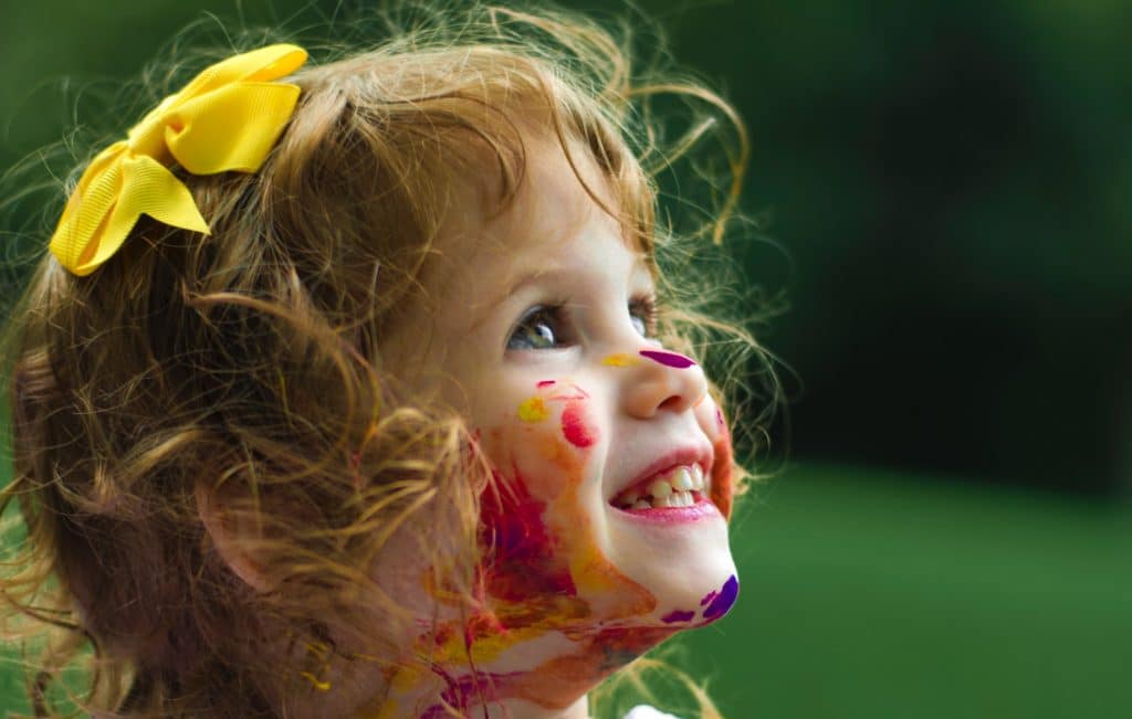 Little girl at a child care center with paint on her face.