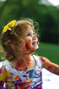 Little girl with a yellow bow in her hair and paint on her face at a child care center.